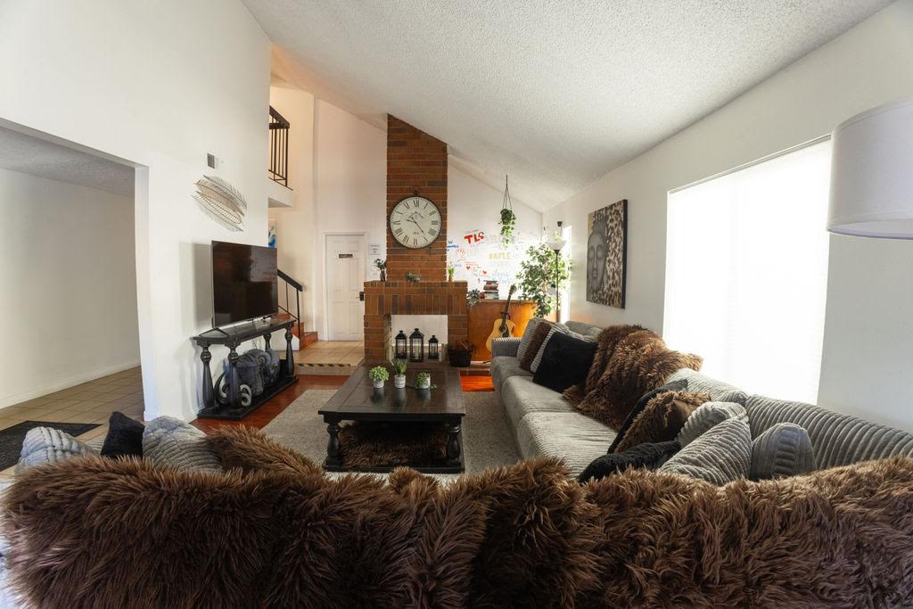 The Home B living room seen from the sofa, with faux-fur throws, a dark coffee table, the TV and the brick fireplace