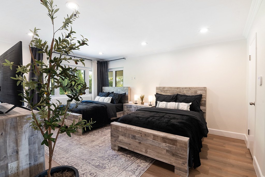 A shared bedroom with two beds, matching wood nightstands and windows onto the trees