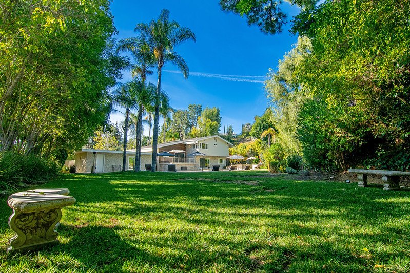 The wide back lawn at the Winnetka home, with stone benches, palm trees and the house in the distance